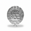 NCC aluminium metal cap badge with embossed ‘NCC’ text and wreath design, lightweight silver-tone finish, featuring crossed torch emblem and attachment loop.